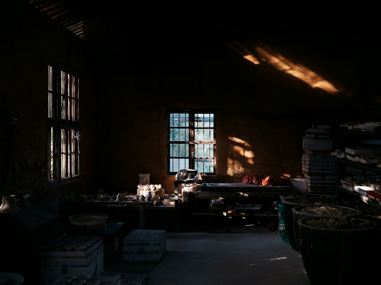 La lumière du soleil traverse un atelier de poterie, illuminant des pièces en argile et en céramique.