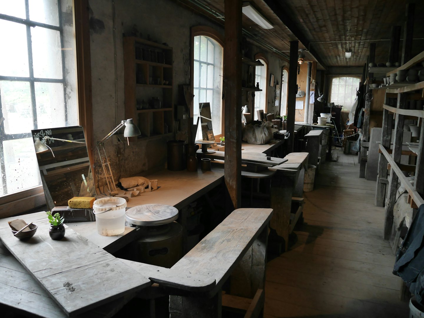Atelier de poterie rustique avec tours, outils et céramiques.