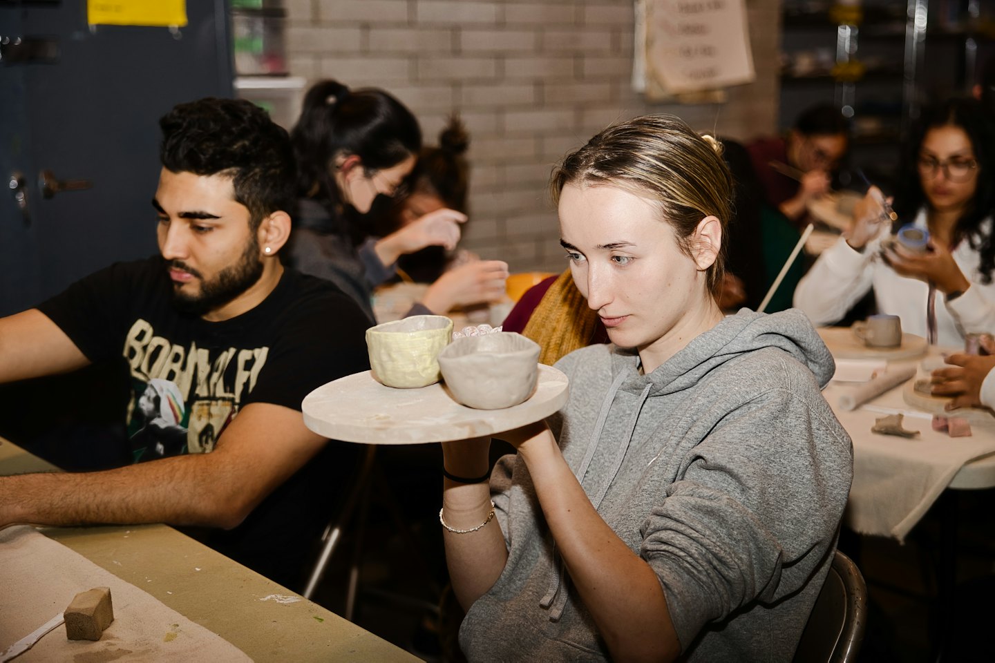De jeunes adultes fabriquent des bols en céramique dans un atelier de poterie.